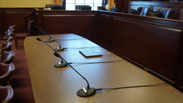 Microphones on table in front of chairs for a committee hearing.