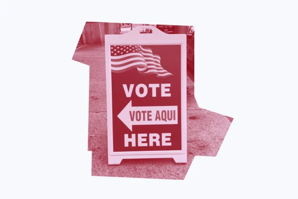 Dark red graphic of a "vote here/vote aqui" sign.