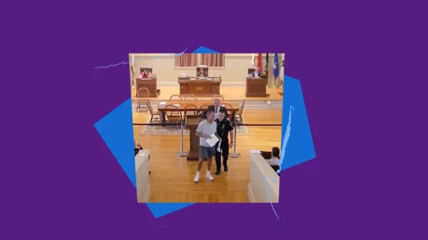 Robert Cote being led out of a Warwick Town Council meeting by a police officer, with purple and blue shapes and squiggles framing the image.
