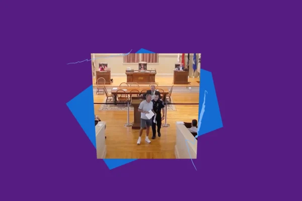 Robert Cote being led out of a Warwick Town Council meeting by a police officer, with purple and blue shapes and squiggles framing the image.