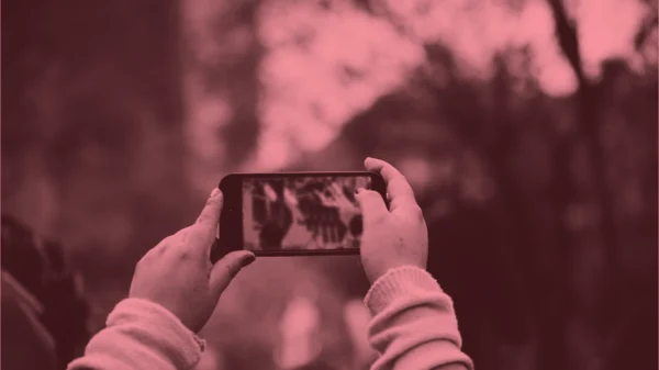 Dark red and pink photo of someone recording on a phone