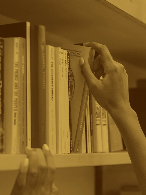 A person taking a book off of a bookshelf