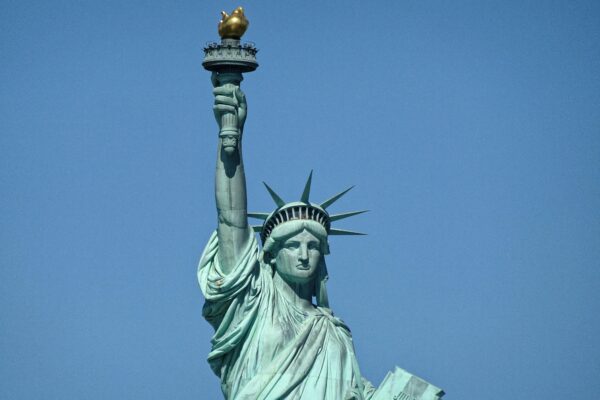 Photo of the statue of liberty against a blue sky.